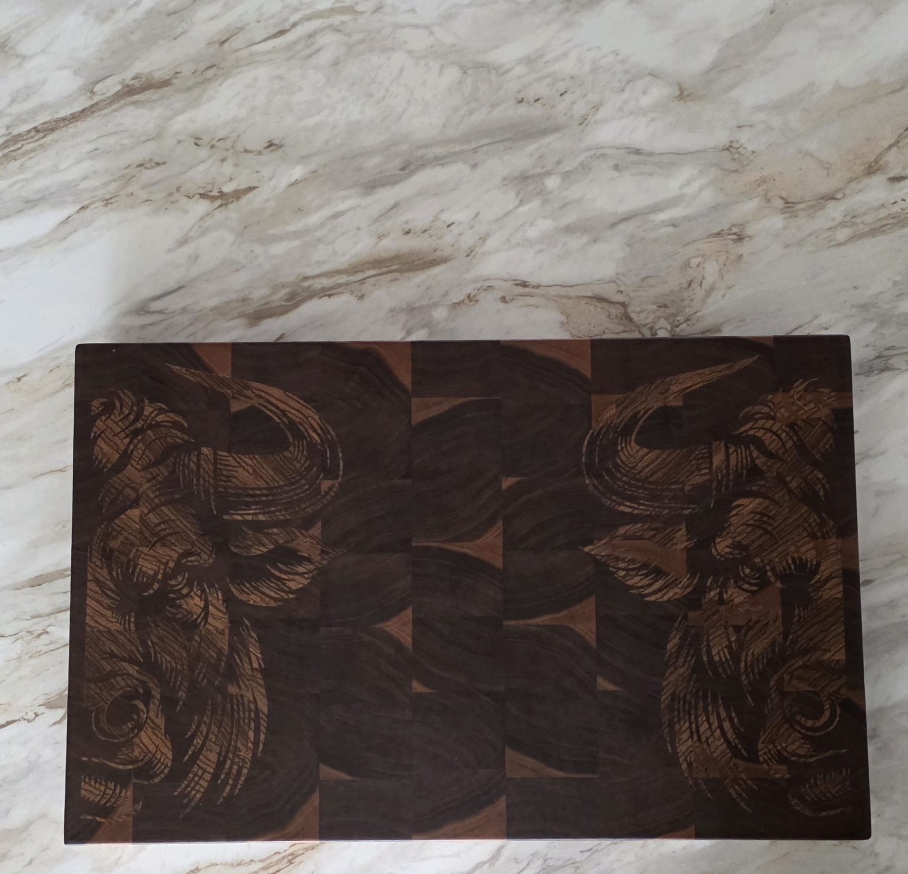 Custom walnut end grain cutting board with a carved relief design