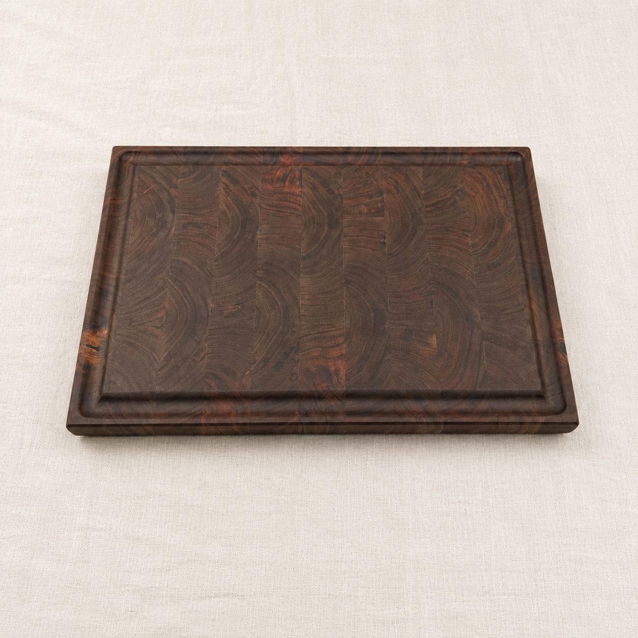 Custom walnut end grain cutting board with a routed juice groove, made in Canada